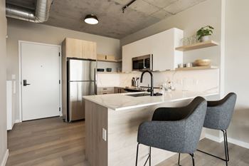 A kitchen with a white countertop and grey chairs.